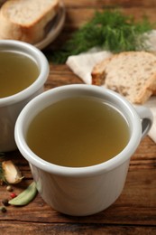 Photo of Hot delicious bouillon in cups on wooden table, closeup