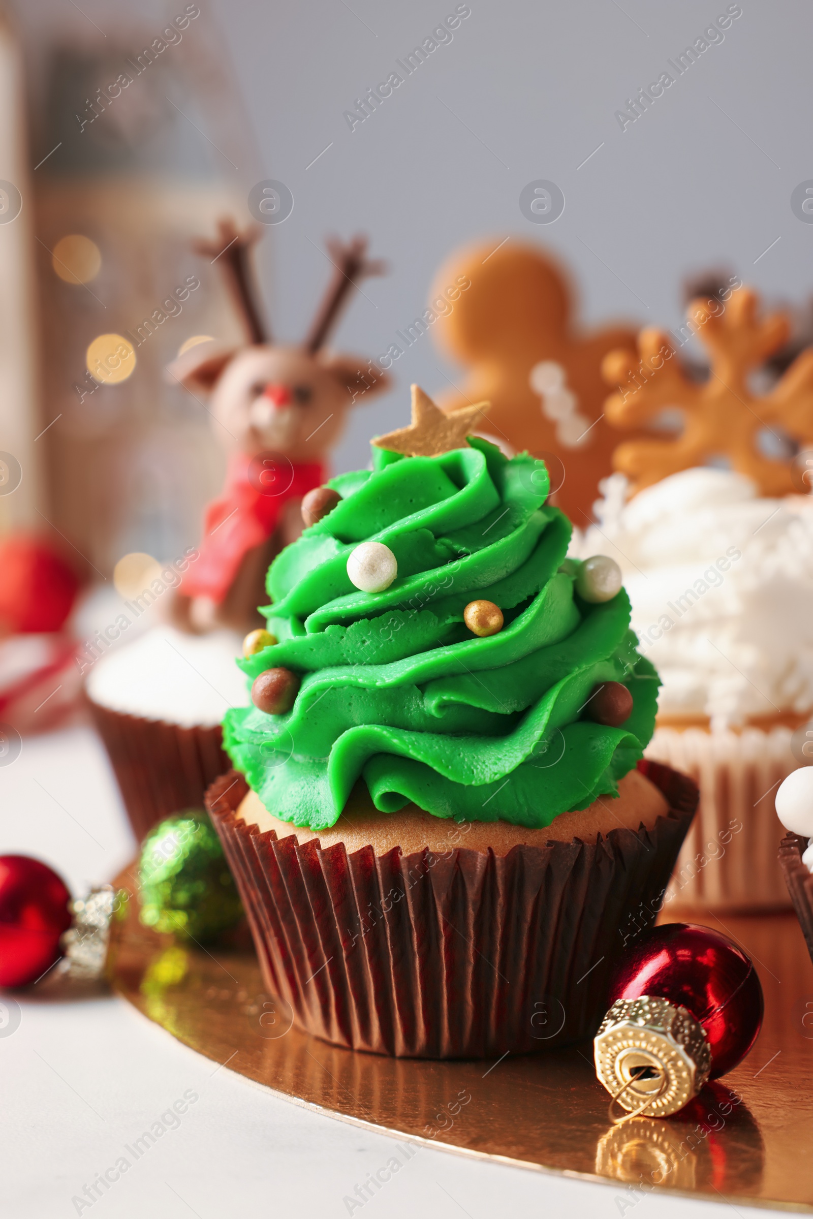 Photo of Tasty Christmas tree cupcake and baubles on white table