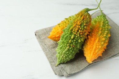 Bitter melons on white marble table, closeup. Space for text