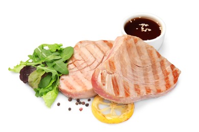 Delicious tuna steaks with salad, sauce and lemon isolated on white