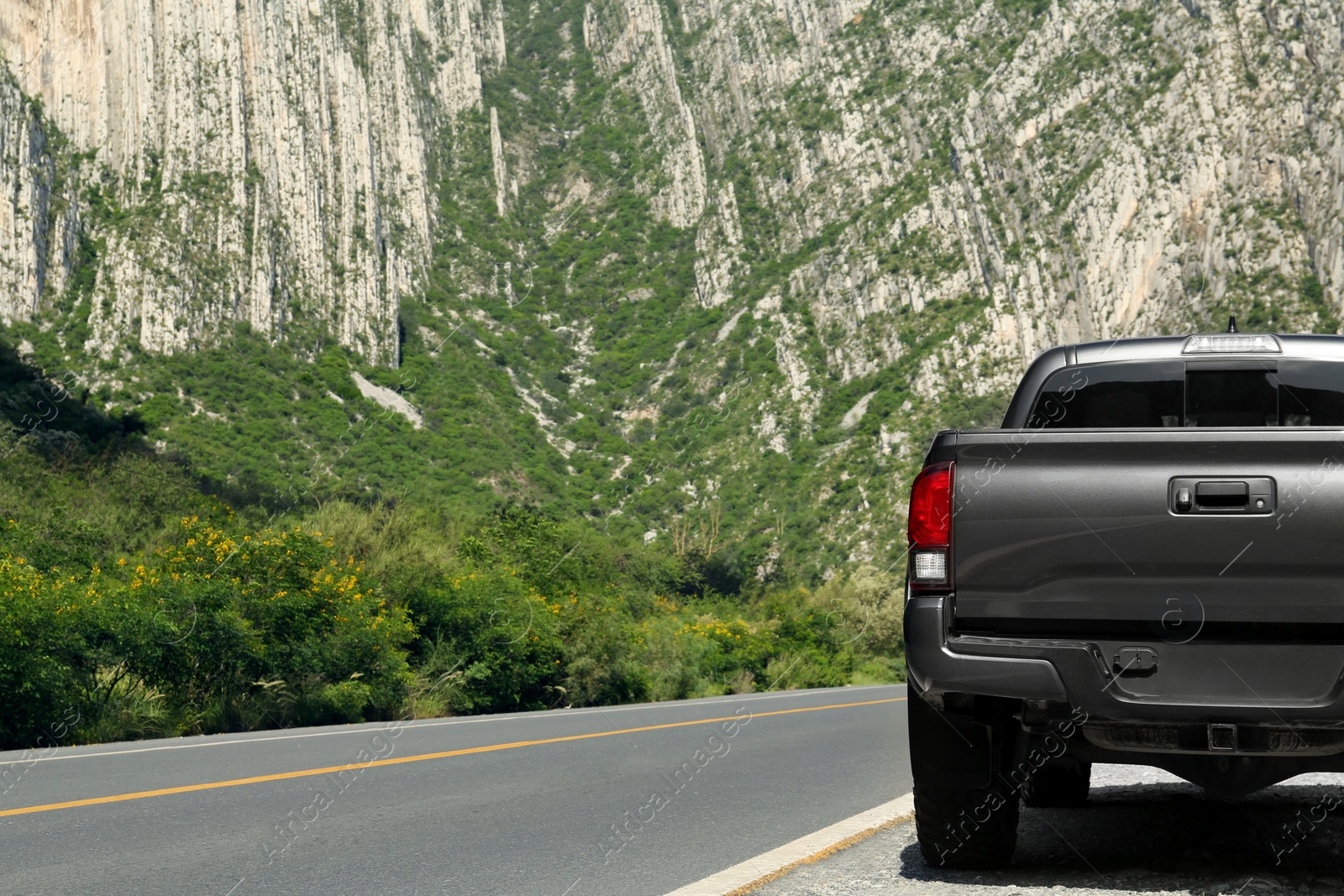 Photo of Picturesque view of big mountains and trees near road with black car, space for text