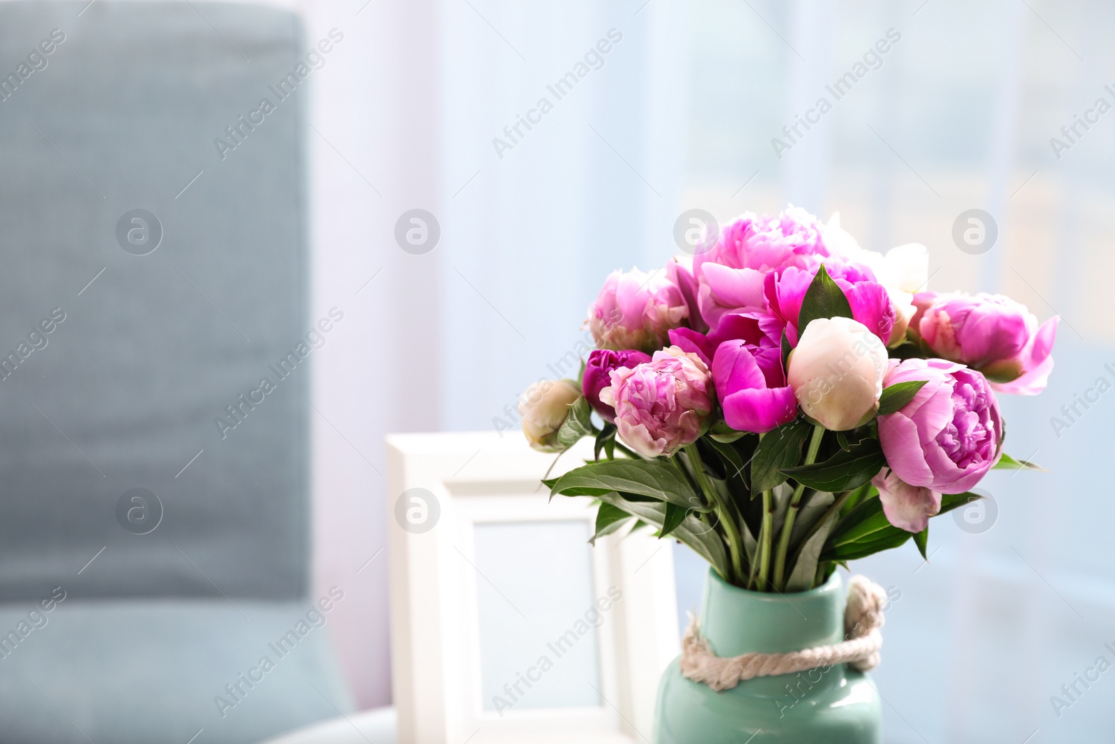 Photo of Vase with bouquet of beautiful peonies in room, space for text