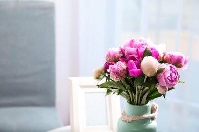 Photo of Vase with bouquet of beautiful peonies in room, space for text