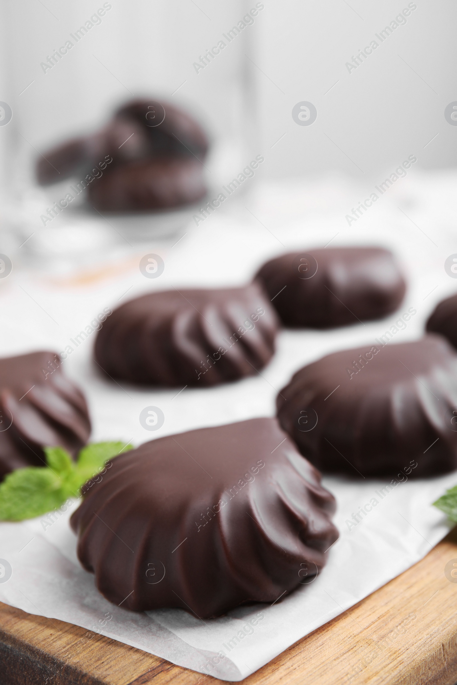 Photo of Delicious chocolate covered zephyrs and mint on wooden board, closeup. Space for text