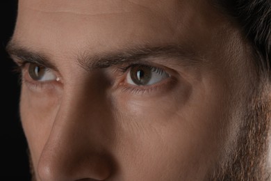 Photo of Evil eye. Man with scary eyes on black background, closeup