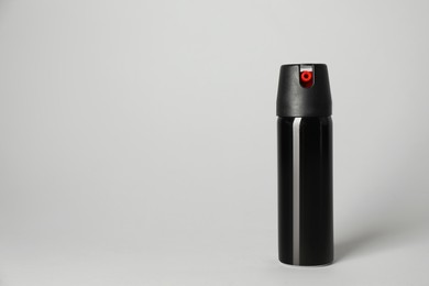 Photo of Bottle of gas pepper spray on light grey background. Space for text