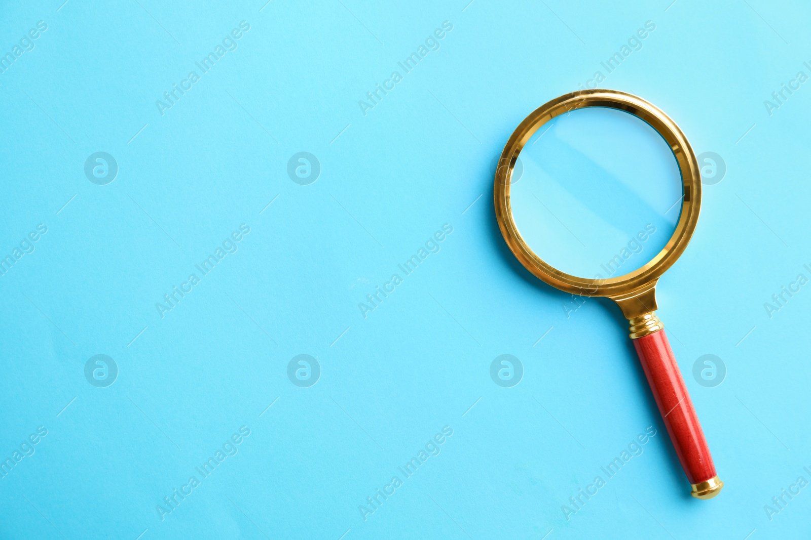 Photo of Top view of magnifier glass on light blue background, space for text. Find keywords concept