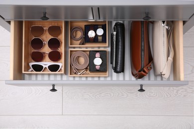 Photo of Open drawer with different stylish accessories indoors, top view. Storage and organizing