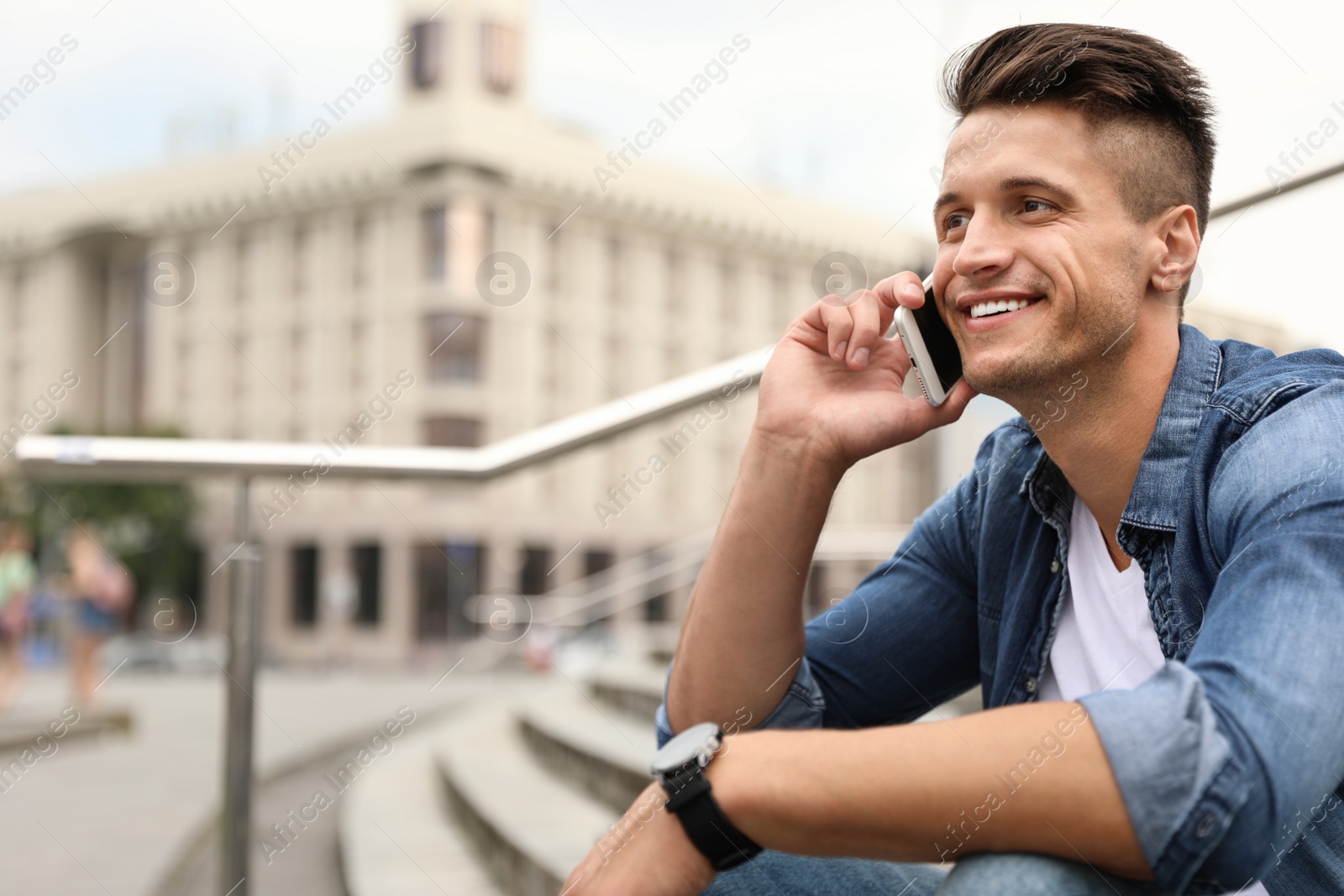 Photo of Portrait of handsome young man talking on phone outdoors. Space for text