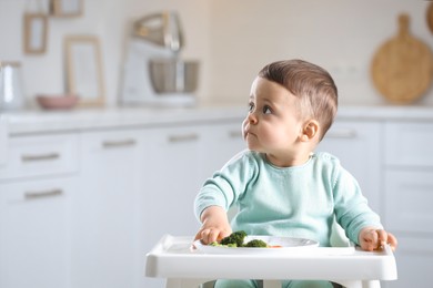 Photo of Cute little baby eating healthy food in high chair at home. Space for text