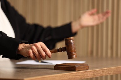 Photo of Judge striking mallet at wooden table indoors, closeup. Space for text