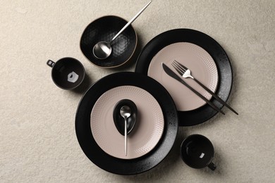Stylish table setting. Dishes, cutlery and cups on light surface, flat lay
