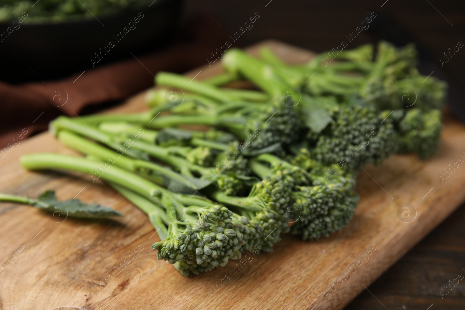 Photo of Fresh raw broccolini on wooden board, closeup. Healthy food