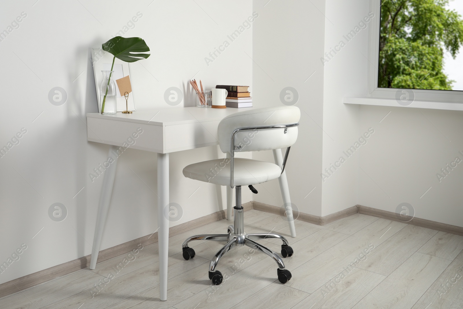 Photo of Comfortable workplace with white desk near wall at home