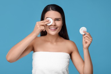 Photo of Young woman with cotton pads on light blue background