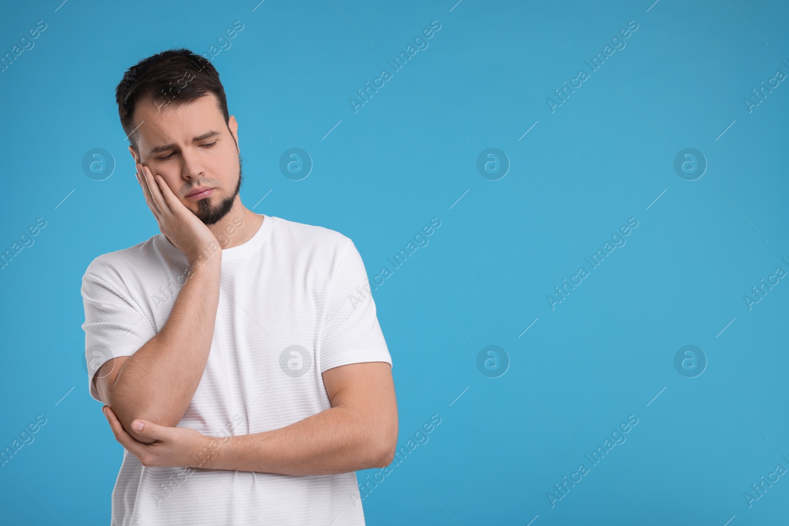 Photo of Portrait of sad man on light blue background, space for text