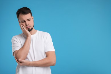 Portrait of sad man on light blue background, space for text