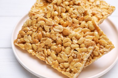 Photo of Delicious peanut bars (kozinaki) on white wooden table, closeup