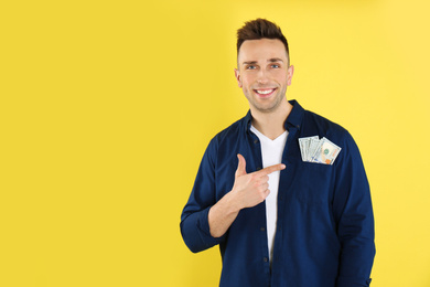 Photo of Happy man with cash money on yellow background. Space for text