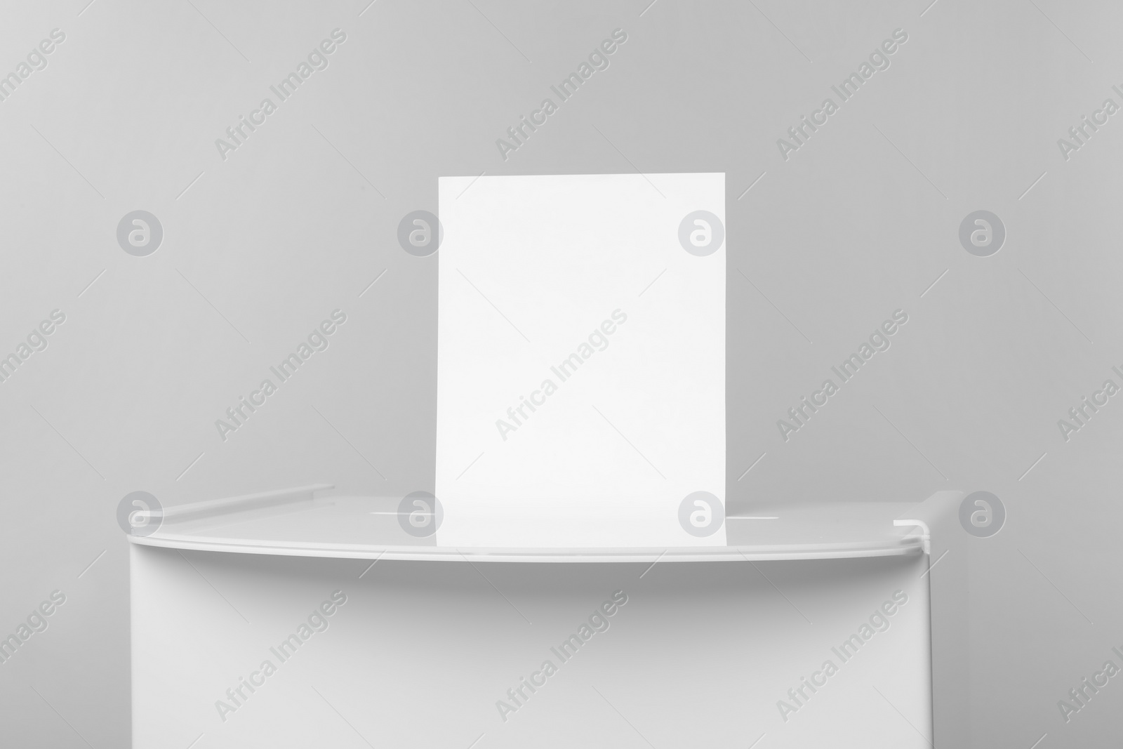 Photo of Ballot box with vote on light grey background, closeup. Election time