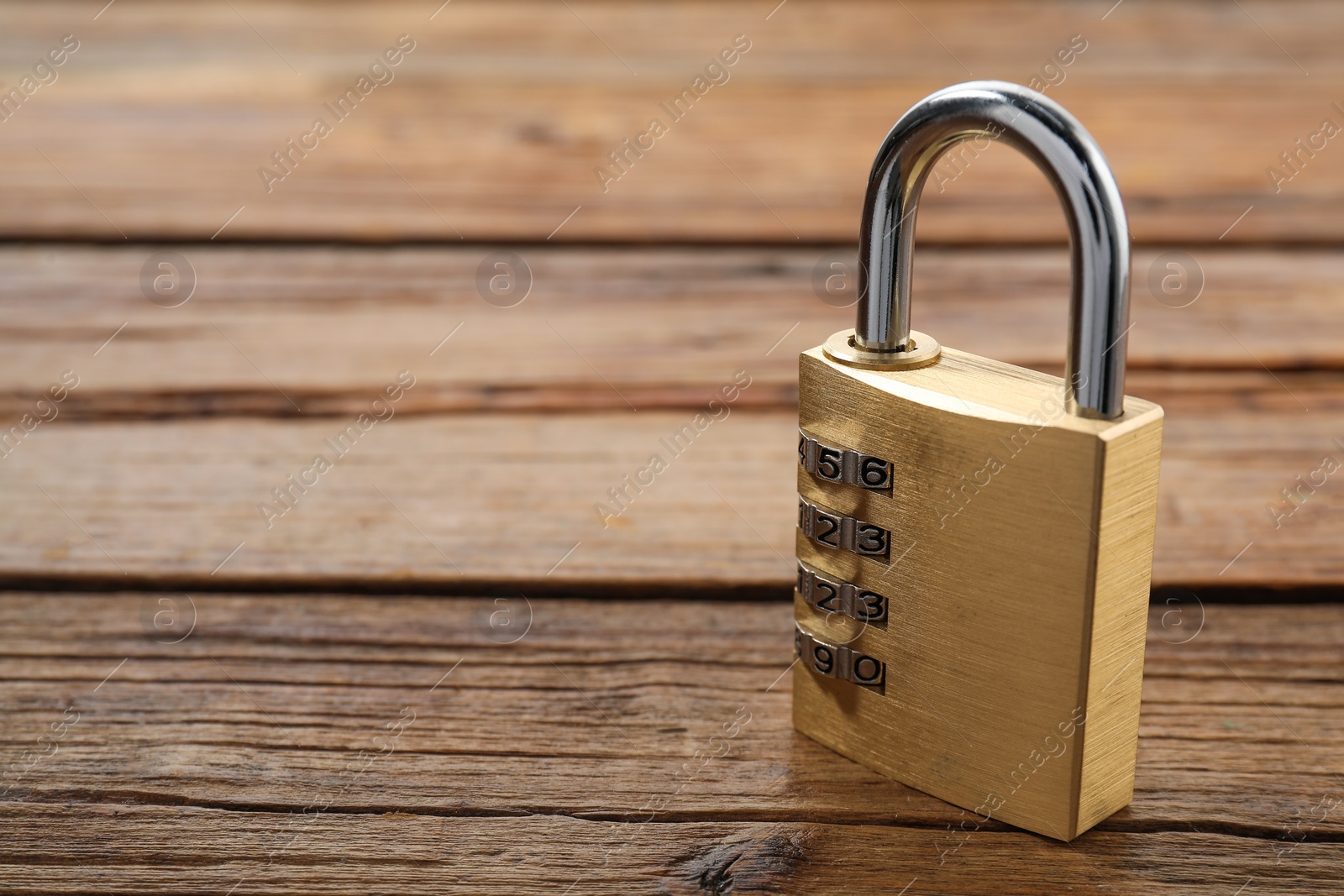 Photo of One steel combination padlock on wooden table, closeup. Space for text