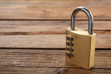 Photo of One steel combination padlock on wooden table, closeup. Space for text