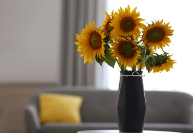 Photo of Vase with beautiful yellow sunflowers on table in room, space for text