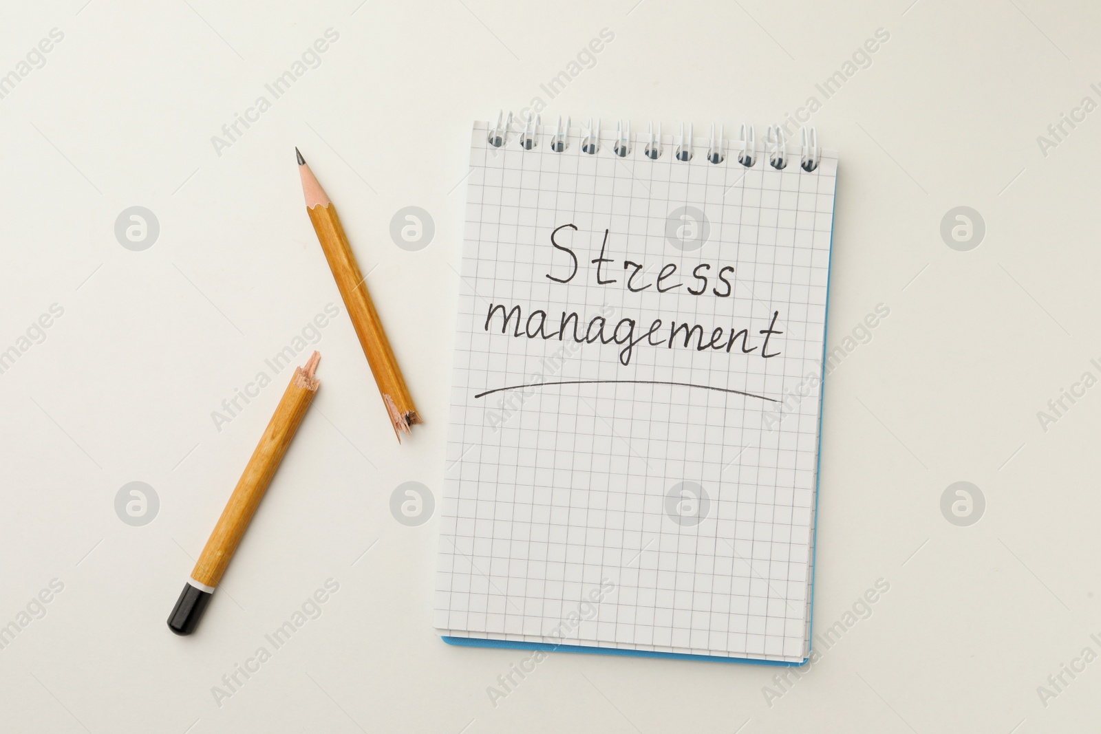 Photo of Broken pencil and notepad with inscription Stress Management on white background, flat lay