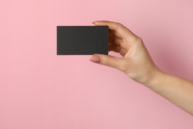 Photo of Woman with blank black business card on pink background, closeup. Mockup for design