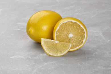 Photo of Whole and cut fresh ripe lemons on grey marble table