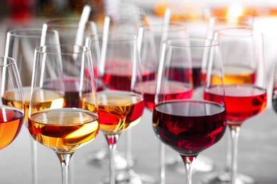 Glasses with different wines on blurred background, closeup