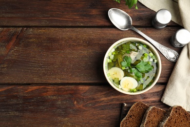 Delicious sorrel soup with eggs served on wooden table, flat lay. Space for text
