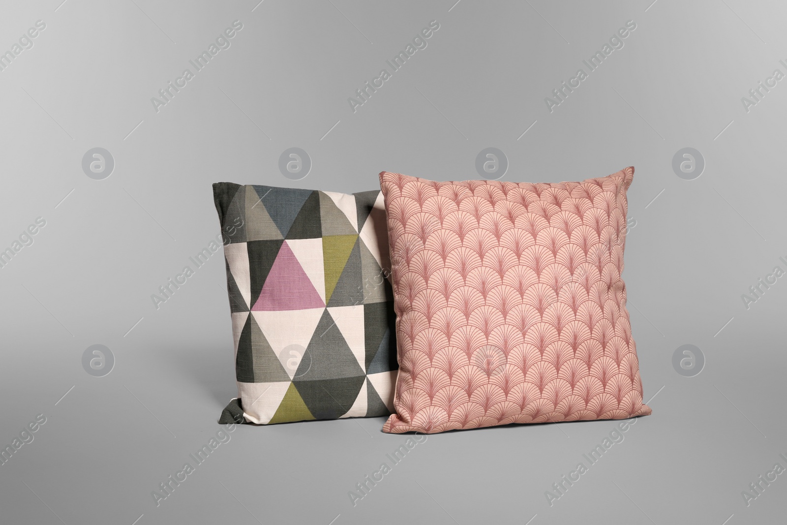 Photo of Two stylish decorative pillows on light background