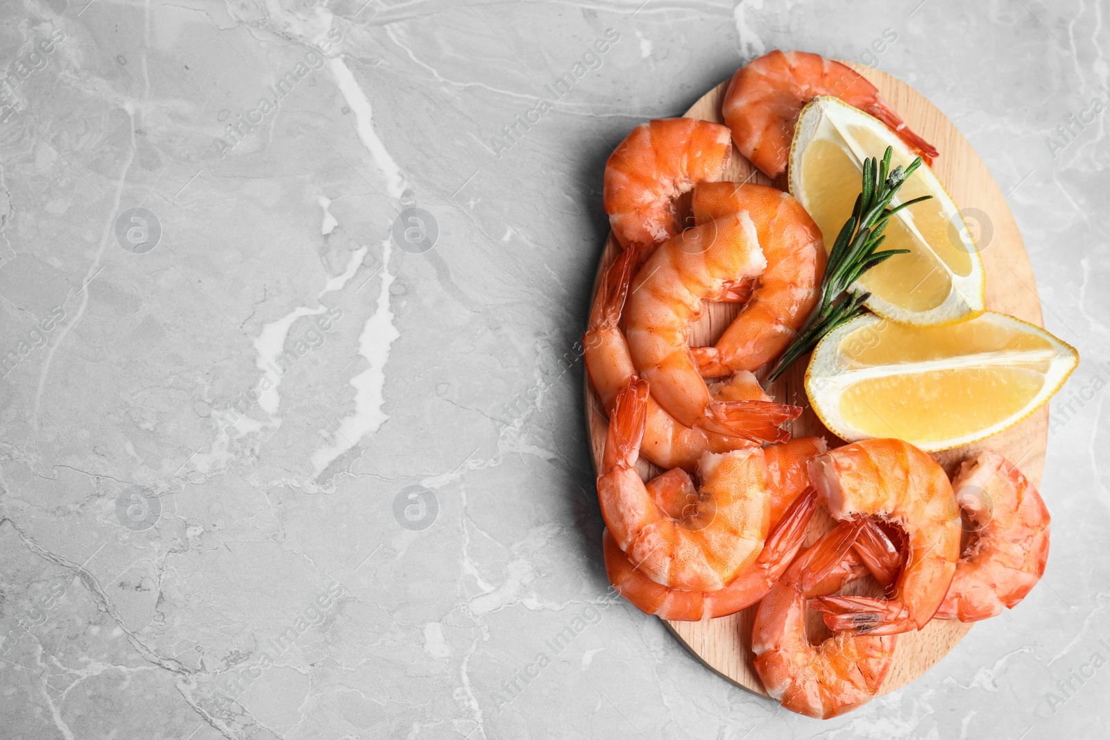 Photo of Delicious cooked shrimps with rosemary and lemon on grey marble table, top view. Space for text