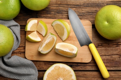 Photo of Flat lay composition with whole and cut sweetie fruits on wooden table