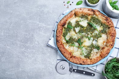 Photo of Delicious pizza with pesto, cheese and arugula served on grey table, flat lay. Space for text