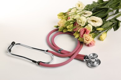 Photo of Stethoscope and eustoma flowers on white background. Happy Doctor's Day