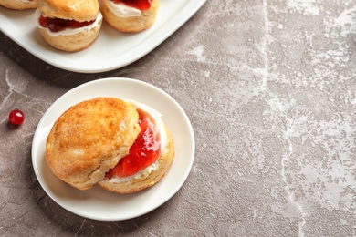 Tasty scone with clotted cream and jam on grey background