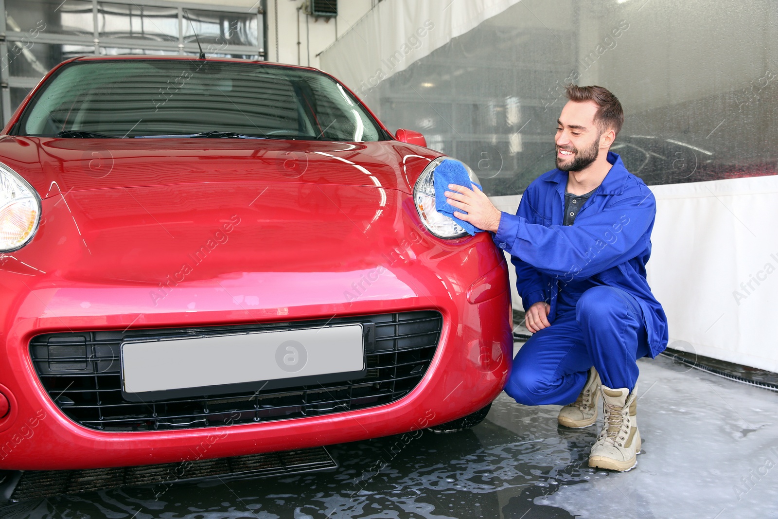 Photo of Worker cleaning automobile headlight with rag at car wash