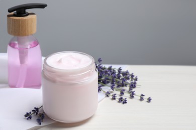 Photo of Jar of hand cream, cosmetic product and lavender on white wooden table, space for text