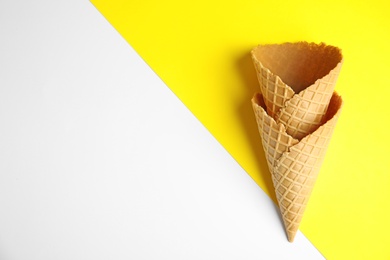 Photo of Empty wafer ice cream cones on color background, flat lay. Space for text