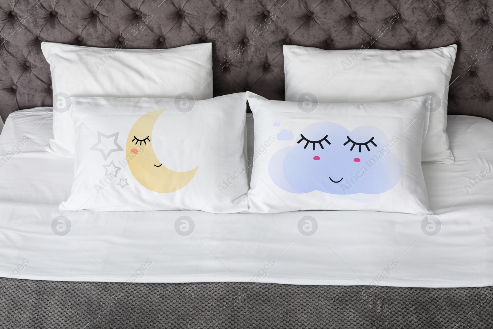Image of Soft pillows with cute faces on comfortable bed 