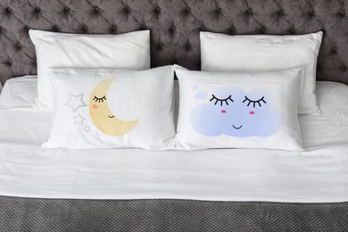 Image of Soft pillows with cute faces on comfortable bed 