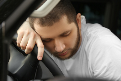Photo of Tired man sleeping on steering wheel in his car, closeup