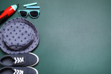 Photo of Flat lay composition with shoes, hat and child accessories on green chalkboard, space for text. School holidays