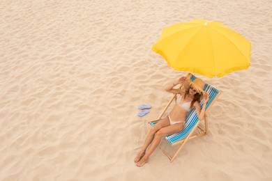 Image of Woman resting in sunbed under yellow beach umbrella at sandy coast, space for text