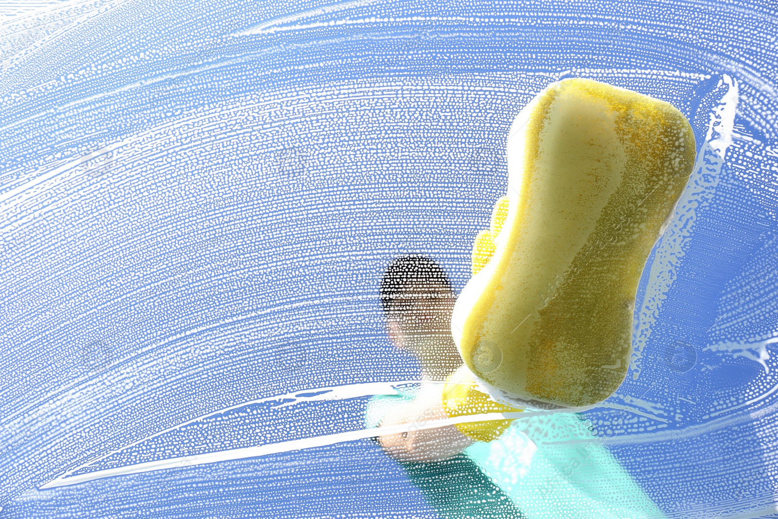 Photo of Woman cleaning glass with sponge on sunny day