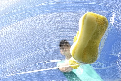 Photo of Woman cleaning glass with sponge on sunny day