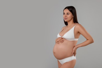 Beautiful pregnant woman in stylish comfortable underwear on grey background, space for text