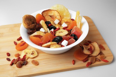Bowl with different dried fruits on white background